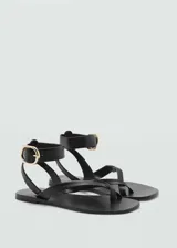 Sandalias de cuero negras con tira entre los dedos y pulsera al tobillo con hebilla dorada.