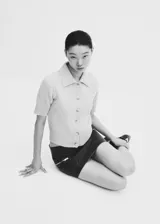 Cardigan tejido de punto color durazno, con cuello camisero, manga corta y cierre frontal con botones.