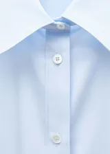 Camisa celeste de popelina de algodón y lyocell, de corte oversize, manga larga con puños abotonados, cuello camisero y cierre frontal con botones.