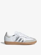 Zapatillas Adidas Samba OG blancas con detalles en plateado y suela de goma color caramelo.