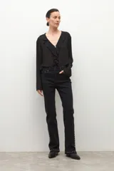 Jean negro de tiro medio, corte bootcut, con tachas metálicas plateadas decorando los laterales de las piernas y el ruedo.