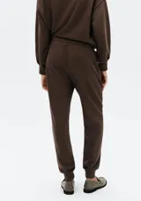 Pantalón de jogging color gris claro, con cintura elástica ajustable con cordón y puños ajustados en los tobillos.