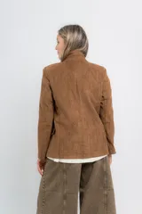 Blazer color camel tostado de gamuza sintética, con corte entallado, largo a la cadera, doble abotonadura frontal y bolsillos con tapa.