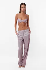 Pantalón de tela glitter color lila, de corte sastrero clásico y tiro medio. Tiene pasacinto, cierre con gancho metálico y cierre en cartera, bolsillos laterales diagonales y bolsillos traseros ribete falsos.
