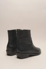 Bota corta de cuero vacuno color negro, con punta fina y taco bajo.