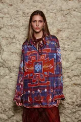 Camisa holgada estampada con motivos geométricos en tonos azul, rojo y marrón. Tiene cuello solapa, mangas largas y cierre abotonado.