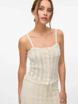 Top de tejido de punto color blanco hueso, con tirantes finos y escote cuadrado ribeteado con ondas. Presenta una hilera de botones frontales.