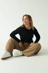 Sweater negro de punto con diseño trenzado, corte cropped, cuello redondo y mangas largas.