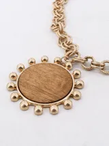 Collar dorado con cadena de eslabones y dije circular de madera con borde de bolitas doradas.