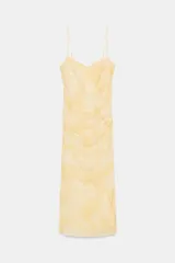 Vestido midi de tejido mesh color amarillo pálido con estampado tipo tie-dye o acuarela en tonos más oscuros. Presenta escote en pico, tirantes finos ajustables y drapeado frontal.