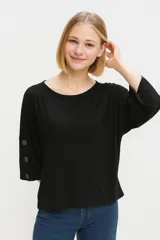 Remera negra de viscosa y elastano, manga 3/4 con botones en los puños, holgada y con cuello redondo.