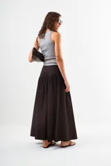 Falda larga de color negro, con cintura lisa y un amplio volado fruncido que comienza a la altura de la cadera, aportando volumen y movimiento.