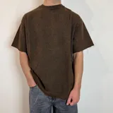 Remerón marrón con efecto gastado, corte oversize, cuello redondo y mangas cortas con terminación desflecada.