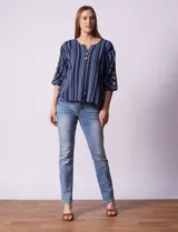 Blusa de algodón con estampado a rayas verticales en tonos celeste, rosa y blanco. Tiene cuello redondo con escote en V y abertura con botones de madera. Las mangas son 3/4 con aplique de botones.