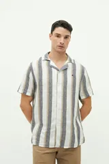 Camisa de manga corta confeccionada en lino y algodón a rayas verticales en tonos blanco, gris y beige. Tiene cuello tipo cubano, corte regular y logo bordado en el pecho.