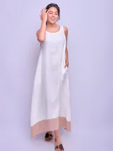 Vestido largo sin mangas color beige con ruedo verde, de corte amplio y estilo casual.