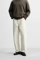 Pantalón de jean color crudo, corte amplio y tiro alto, con cinco bolsillos y cierre frontal con botones.