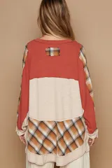 Blusa oversize estilo patchwork, con combinación de paneles lisos y a cuadros. Mangas largas holgadas con puños y tapeta con botones metálicos.
