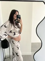 Conjunto de pijama blanco con estampado de tigres negros, ribetes negros, camisa de manga larga con botones y pantalón largo.