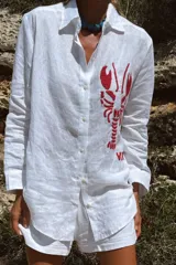 Camisa blanca de lino con bordado de langosta roja en el frente.