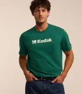 Remera blanca de algodón con cuello redondo y mangas cortas. Estampa frontal con el logo de Kodak en azul.
