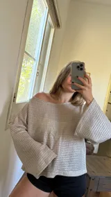 Blusa plateada de tejido metalizado, con escote en bote que puede usarse recto o caído en un hombro.