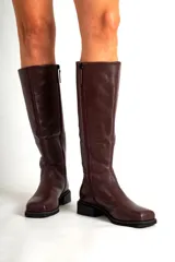 Botas de cuero de caña alta, con punta cuadrada y taco bajo. Disponibles en color bordó y negro.