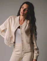 Chaqueta bomber color beige, marca Elan, con cuello a la base, abertura central con botones, bolsillos simulados en la parte delantera y mangas largas con puños.