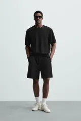Bermuda negra de corte relaxed fit, con cintura elástica ajustable con cordón, bolsillos frontales y bolsillo trasero de parche.