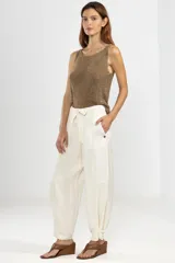 Pantalón de trabajo color crema, de corte relajado, confeccionado en lino y tencel. Con bolsillos laterales, cintura elástica, cordón ajustable y detalle regulable en el tobillo.