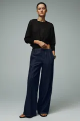 Pantalón de jean azul oscuro, de tiro alto y pierna ancha, con cintura elástica ajustable con cordones y bolsillos delanteros.