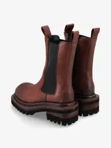 Bota de cuero premium color negro, de diseño minimalista estilo Chelsea con elásticos laterales y tiradores superiores. Posee una suela track de goma con plataforma y taco cuadrado con detalle de madera.