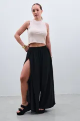 Pantalón palazzo negro con cintura elástica y aberturas laterales altas.