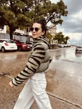 Campera puffer cropped negra con mangas y capucha de polar estampado con diseño geométrico en tonos beige, marrón y negro.