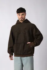 Buzo canguro negro con capucha, calce oversize, confeccionado en frisa 100% algodón con lavado gastado y aplique cosido en el pecho.