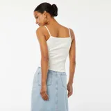 Camiseta sin mangas blanca de canalé con tirantes finos y detalle de encaje en el escote.