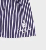 Short tipo bóxer de popelina de algodón a rayas verticales azules y blancas, con cintura elástica, botones frontales y logo bordado en blanco. Confeccionado en Portugal.