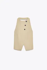 Top chaleco color beige de cuello halter con espalda descubierta y trabilla con hebilla metálica. Cierre frontal con botones y ganchos metálicos.
