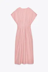 Vestido midi color marrón confeccionado en hilatura con mezcla de algodón y lino. Tiene cuello redondo, manga corta caída y detalle de pliegues en la cintura. Cierre en la espalda con abertura y botón.