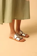 Sandalias plateadas con tiras anchas entrecruzadas y suela plana color camel.