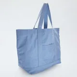 Bolso shopper de tela celeste con bolsillo frontal y asas de hombro.