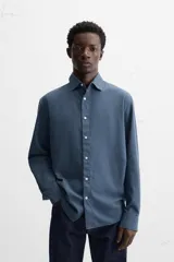 Camisa de vestir azul petróleo, corte regular, confeccionada en mezcla de algodón. Cuenta con cuello solapa, mangas largas con puños abotonados y cierre frontal con botones.