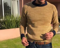 Sweater de lana merino color arena con cuello y puños acanalados en azul marino. Diseño clásico de punto con mangas raglán.