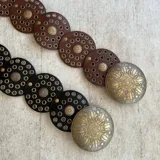 Cinto de cuero marrón y negro con apliques circulares dorados.