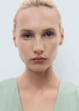 Vestido midi color verde menta, con escote en V, manga corta y diseño evasé. Presenta detalles de costuras y cierre de cremallera en la parte posterior.