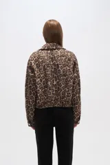 Campera corta con cierre frontal, cuello camisero, puños elastizados y estampado animal print de leopardo en tonos marrones.