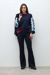 Sweater azul marino con cuello redondo y ribete rojo. Mangas anchas con diseño de jacquard floral en tonos celestes, rojos y verdes.