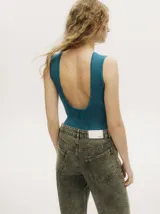 Body acanalado color rojo, de corte cavado con cuello a la base y espalda baja y abierta. Cierre inferior con botones a presión.