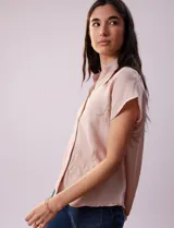Camisa color beige con estampado de hojas marrones, de manga corta, con cuello a la base con solapa y escote en V.