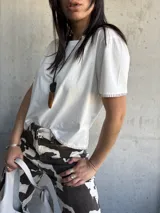 Remera blanca de algodón con cuello redondo y mangas cortas. Presenta terminaciones con costura a la vista en ruedo y mangas.